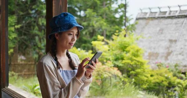 Frau benutzt Handy in japanischem Holzhaus — Stockfoto