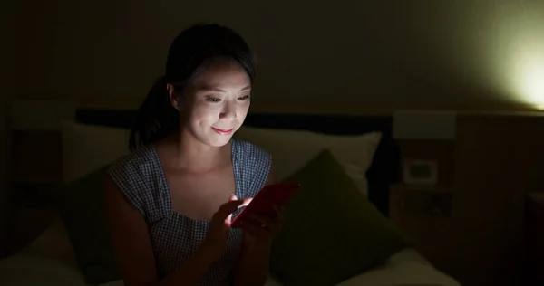 Wanita menggunakan ponsel pintar di tempat tidur di malam hari — Stok Foto