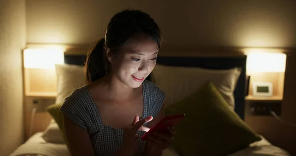 Женщина использование смартфона на кровати ночью — стоковое фото