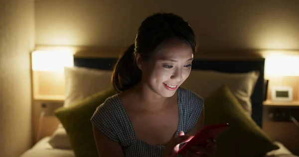 Kvinde brug af smart telefon på hotelværelse om aftenen - Stock-foto