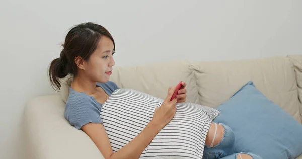 Frau guckt auf Handy und sitzt zu Hause auf Sofa — Stockfoto