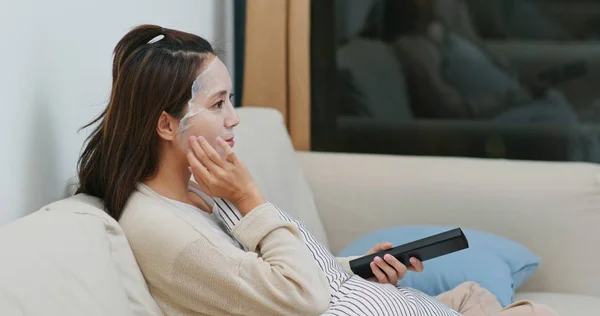 Vrouw van toepassing papieren masker op gezicht en tv kijken thuis — Stockfoto