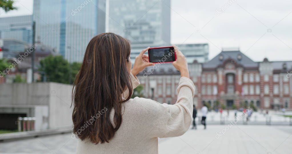 Woman take photo on cellphone in Tokyo station