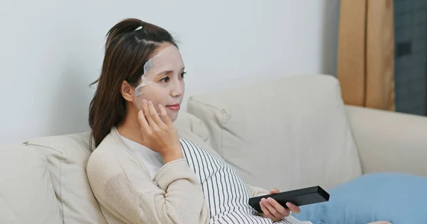 Vrouw van toepassing papieren masker op gezicht en tv kijken thuis — Stockfoto