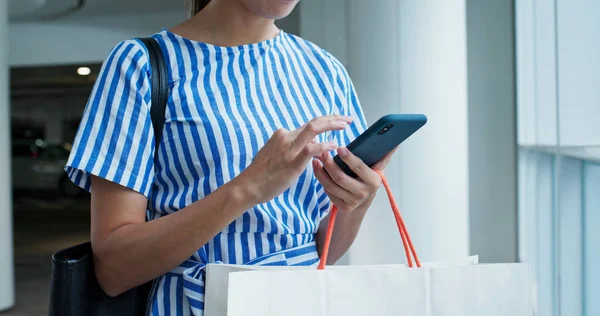 Frau benutzt Handy mit Einkaufstasche — Stockfoto