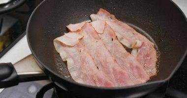 Kahvaltıda kızartma tavasında domuz pastırması pişiriyorum.