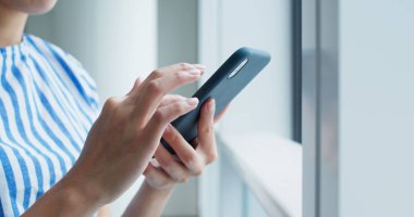 Kadın akıllı telefonu kapalı alanda kullanıyor.