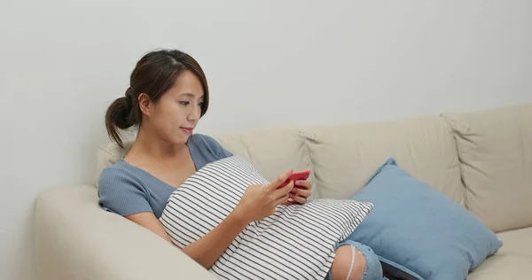 Frau guckt auf Handy und sitzt zu Hause auf Sofa — Stockfoto