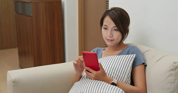 Frau benutzt Handy und sitzt zu Hause auf Sofa — Stockfoto