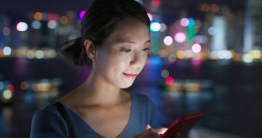 Woman use of mobile phone in city of Hong Kong at night