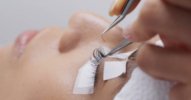 Woman having eyelash extension in beauty salon clipart