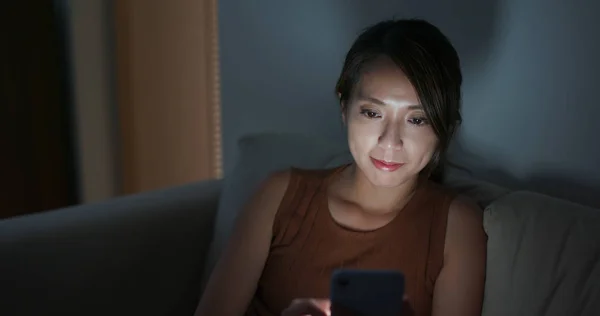 Kobieta korzystająca z telefonu komórkowego w domu wieczorem — Zdjęcie stockowe