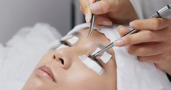 Beauty professional procedures eyelash extension on woman eyes — Stock Photo, Image