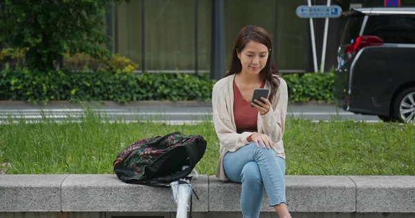 Vrouw gebruik van mobiele telefoon en zitten in het park — Stockfoto