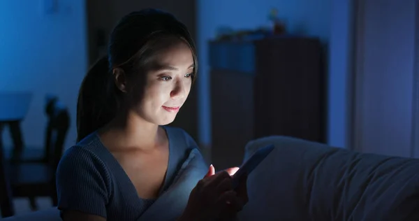 Mulher verificar no telefone inteligente em casa à noite — Fotografia de Stock