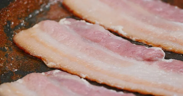 Stekt bacon i kastrull i köket till frukost — Stockfoto