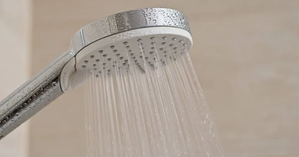 Поток воды из душевой головки в ванной комнате — стоковое фото