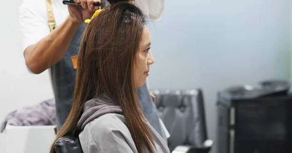 Woman having hair straightening treatment in hair salon