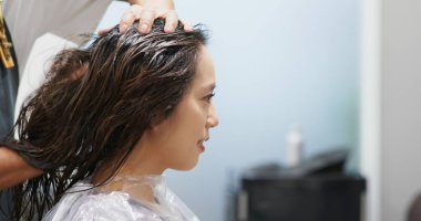 Kadın kuaförde renkli boya yaptırıyor.