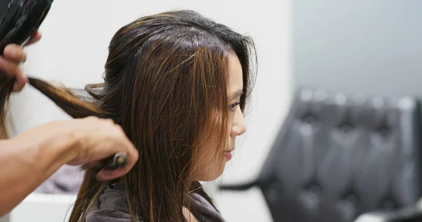 Hair stylist dries client hair in salon — Stok fotoğraf