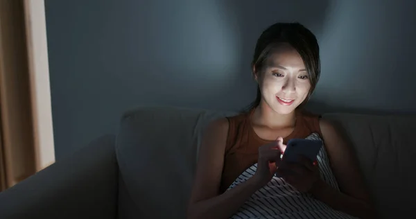 Perempuan menggunakan ponsel di rumah di malam hari — Stok Foto