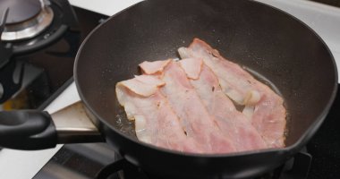 Kahvaltıda kızartma tavasında domuz pastırması pişiriyorum.