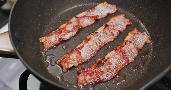 Cottura pancetta sulla padella in cucina per la colazione — Foto Stock