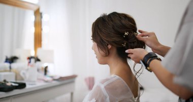 Hairdresser creating a hairstyle for bride in salon