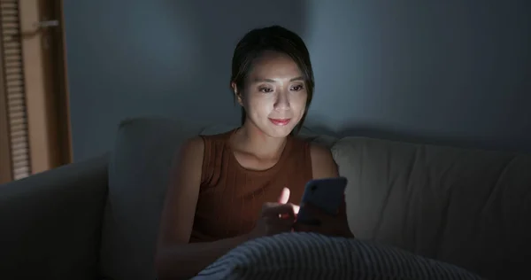 Perempuan menggunakan ponsel di rumah di malam hari — Stok Foto