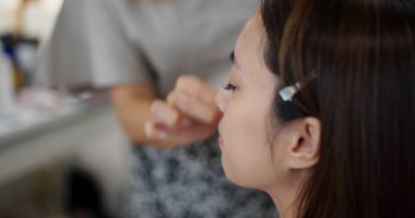 Young woman having make up by artist in the studio