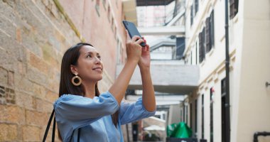Kadın turist Hong Kong şehrini ziyaret ediyor ve cep telefonuyla fotoğraf çekiyor.