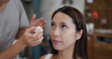 Young woman having make up by artist in the studio