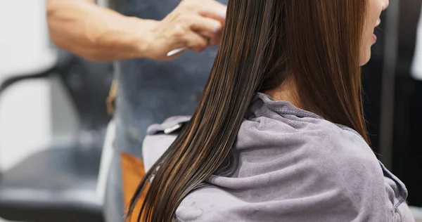 Woman having hair straightening treatment in hair salon