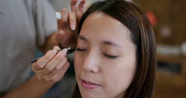 Make up artist shaping eyebrow on female model at studio — Stock Photo, Image