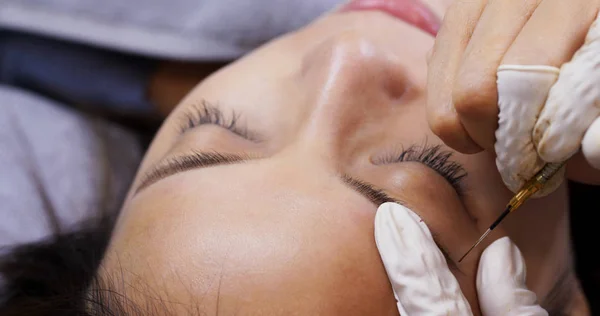 Cosmetólogo aplicando maquillaje permanente en la ceja de la mujer — Foto de Stock