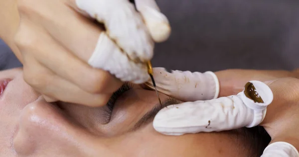 Kosmetolog nakładający stały makijaż na brwi kobiety — Zdjęcie stockowe