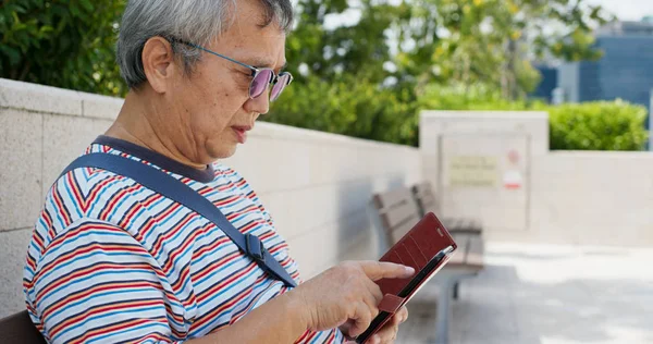 Азиатский старик использует мобильный телефон на открытом воздухе — стоковое фото