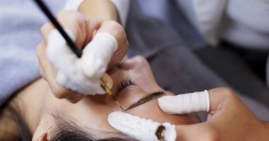 Kozmetik uzmanı kaşlarının kalıcı dövmesini yaptırıyor.