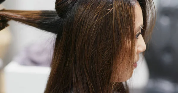 Woman having hair straightening treatment in hair salon