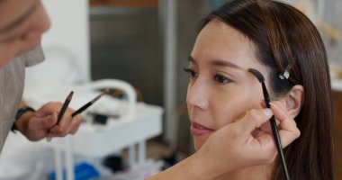 Makyöz güzellik salonunda kaş şekillendirme yapıyor.