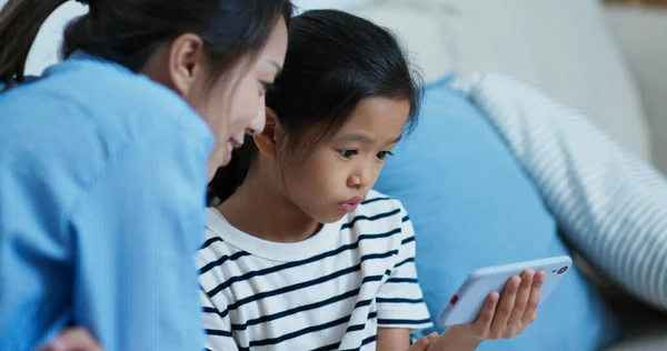 Mère et fille regardent le téléphone portable ensemble à la maison — Photo