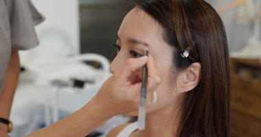 Make up artist do make up on woman model in studio