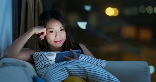 Женщина смотрит на мобильный телефон ночью — стоковое фото