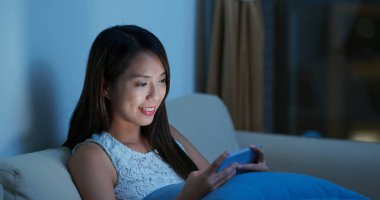 Kadın gece cep telefonundan izliyor.