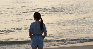 Kadın gün batımında denize bak.