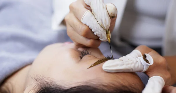 Cosmetologist applying permanent tattooing of eyebrows in beauty