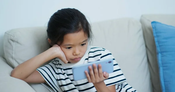 Petite fille regarder sur téléphone portable à la maison — Photo