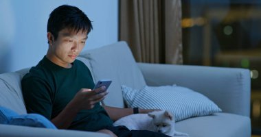 Pomeranya köpeğine cep telefonuyla sarılan bir adam.