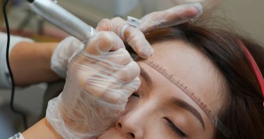 Kadın kaş mikropateni ve kalıcı makyaj yaptırıyor.