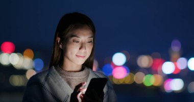 Kadın geceleri cep telefonuna bakar.